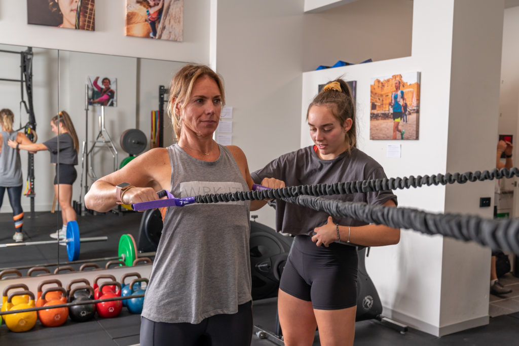 Personal Trainer adjusting woman's technique in strength training session