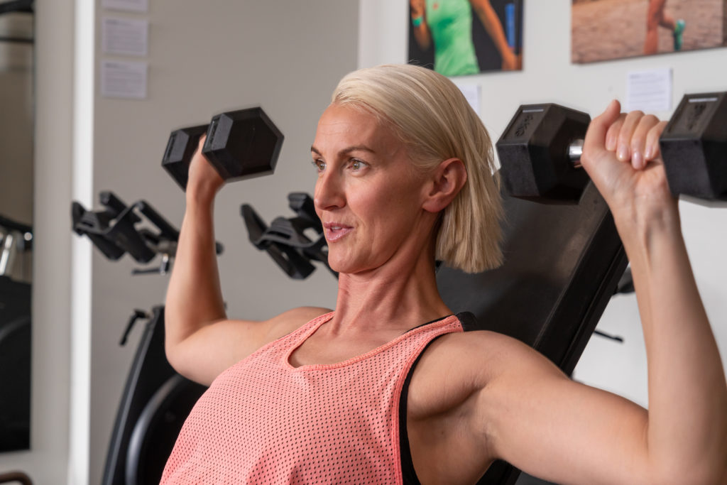 Woman lifting dumbbells in Personal Training session at Strong Women Can