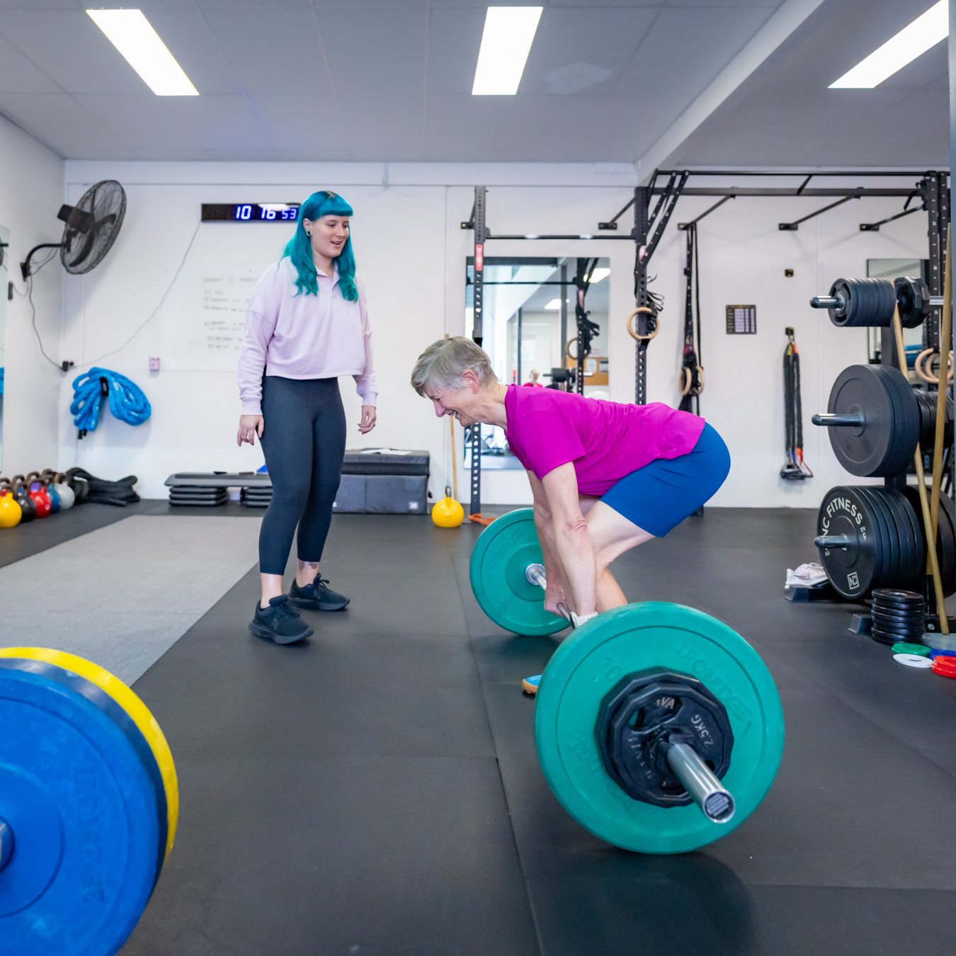 Woman deadlifting with help of Personal Trainer
